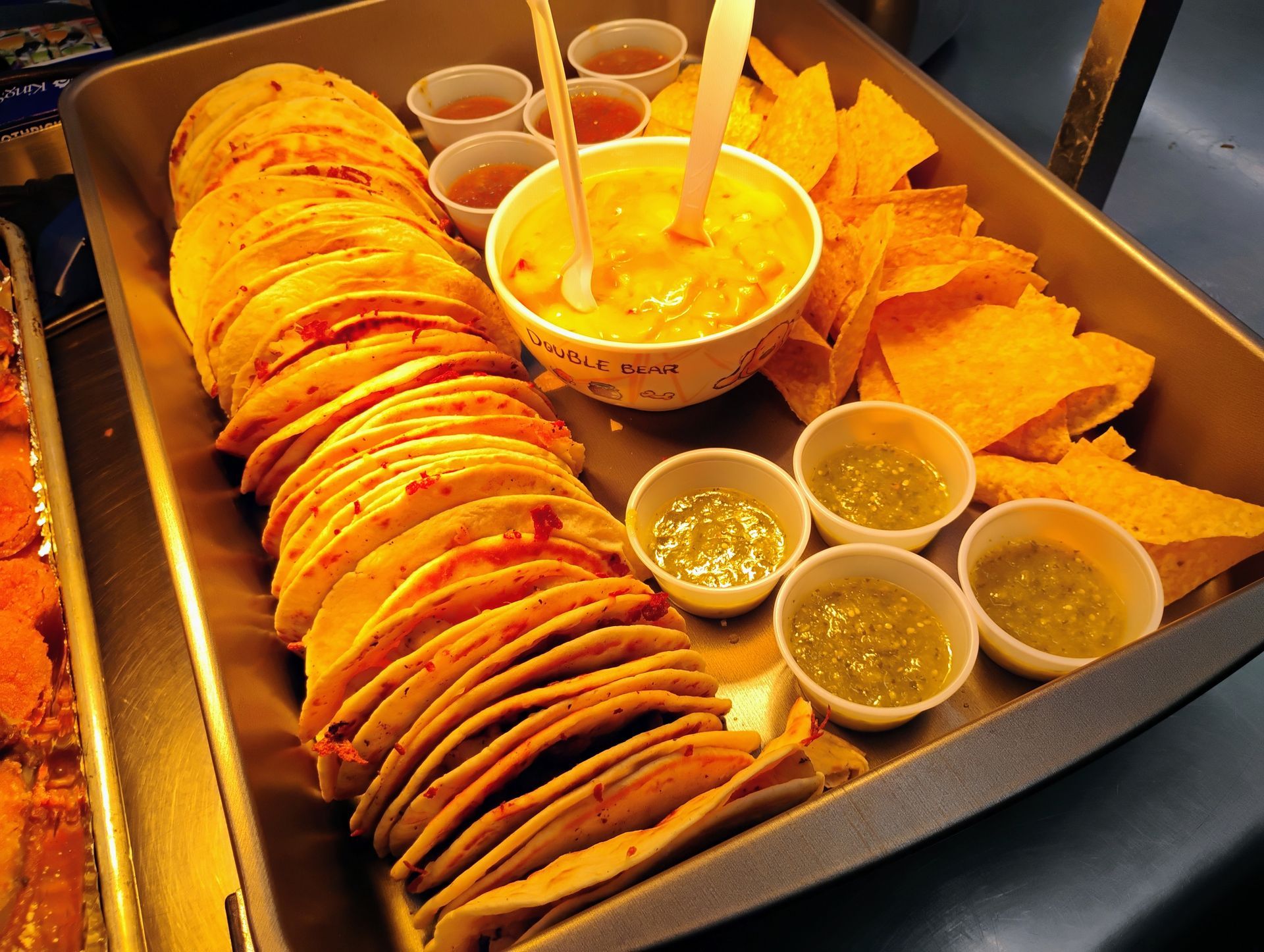 Tray of rolled crepes with sauces and tortilla chips, a warm orange dessert spread