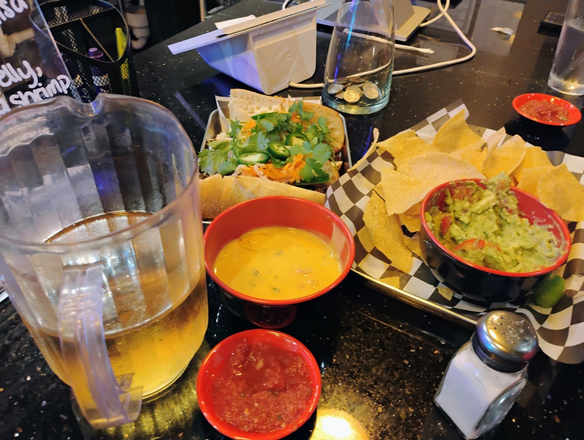 Restaurant table with water, salsa, guacamole, chips, and bowls of dip and soup