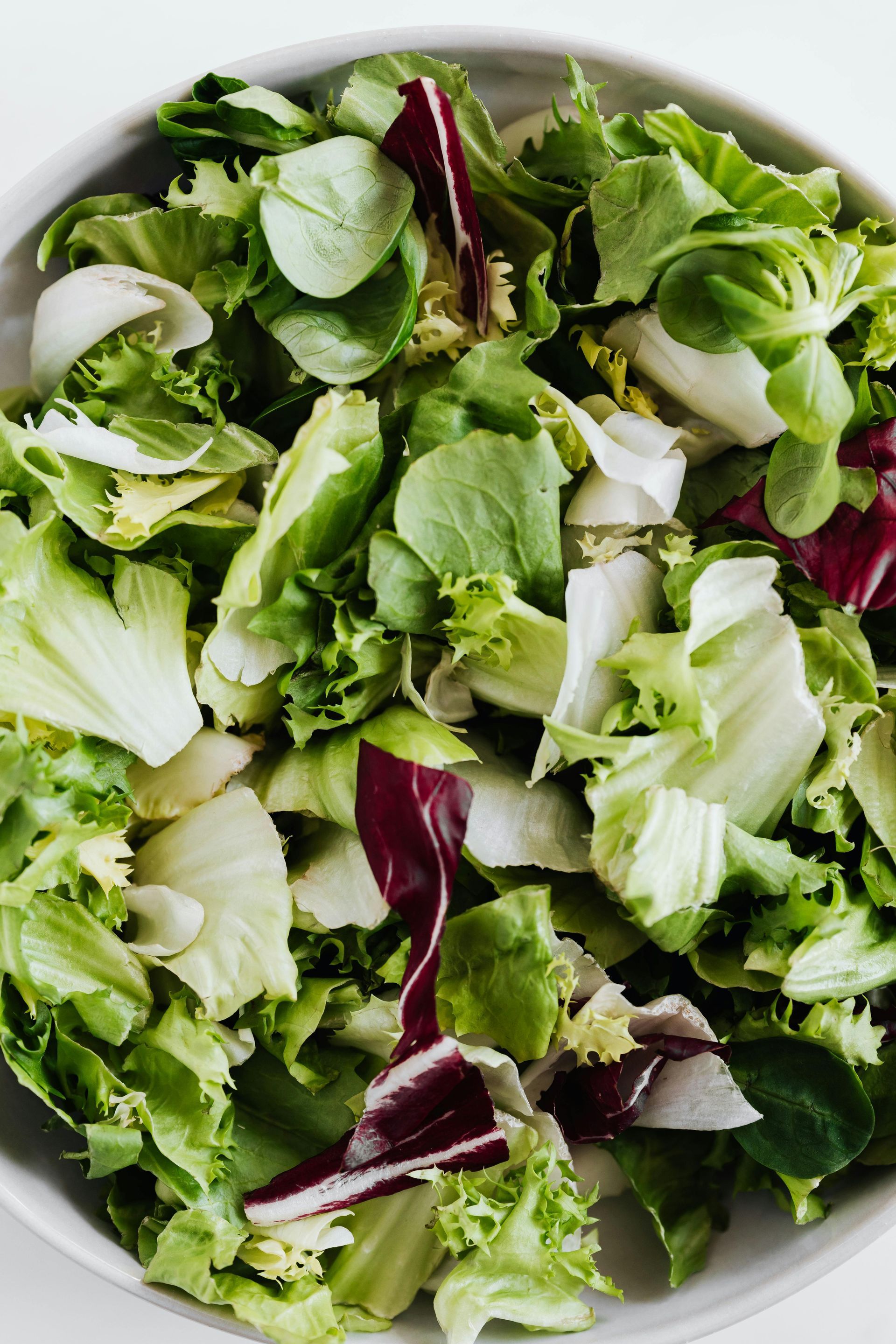 Bowl of mixed green and red leaf salad on a white plate