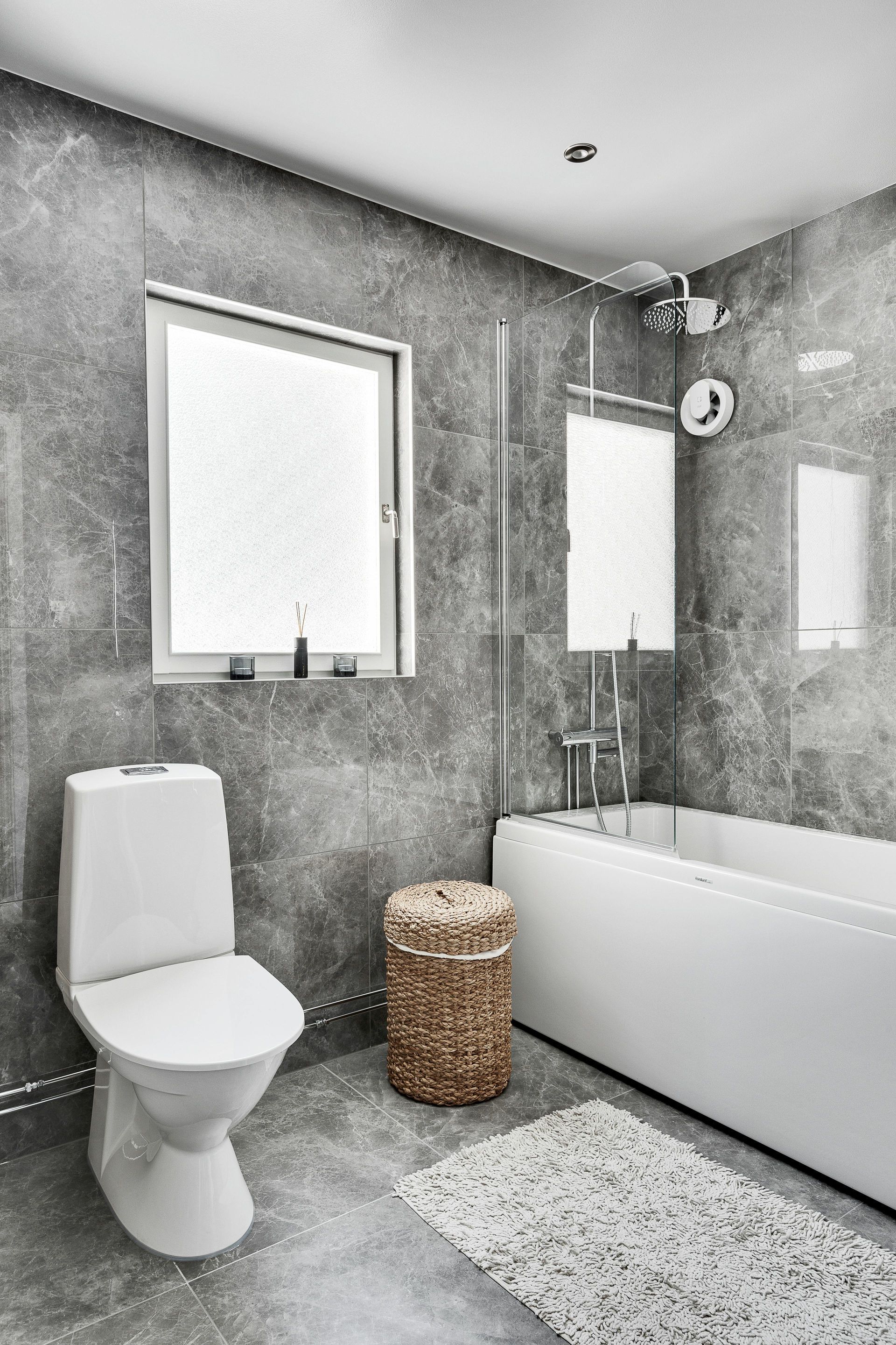 A bathroom with a toilet , bathtub and window.