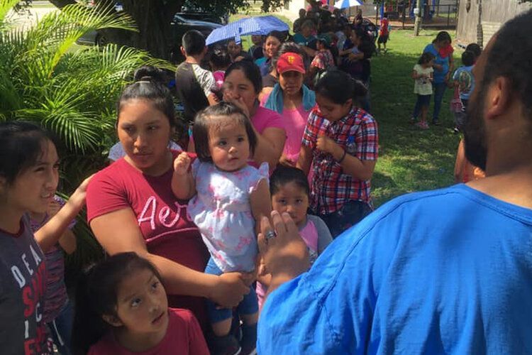 A group of people are standing in a line holding children.