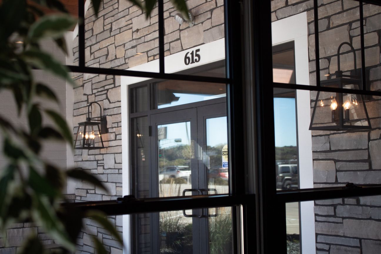 Glass entryway to building 615 with stone facade and hanging lights
