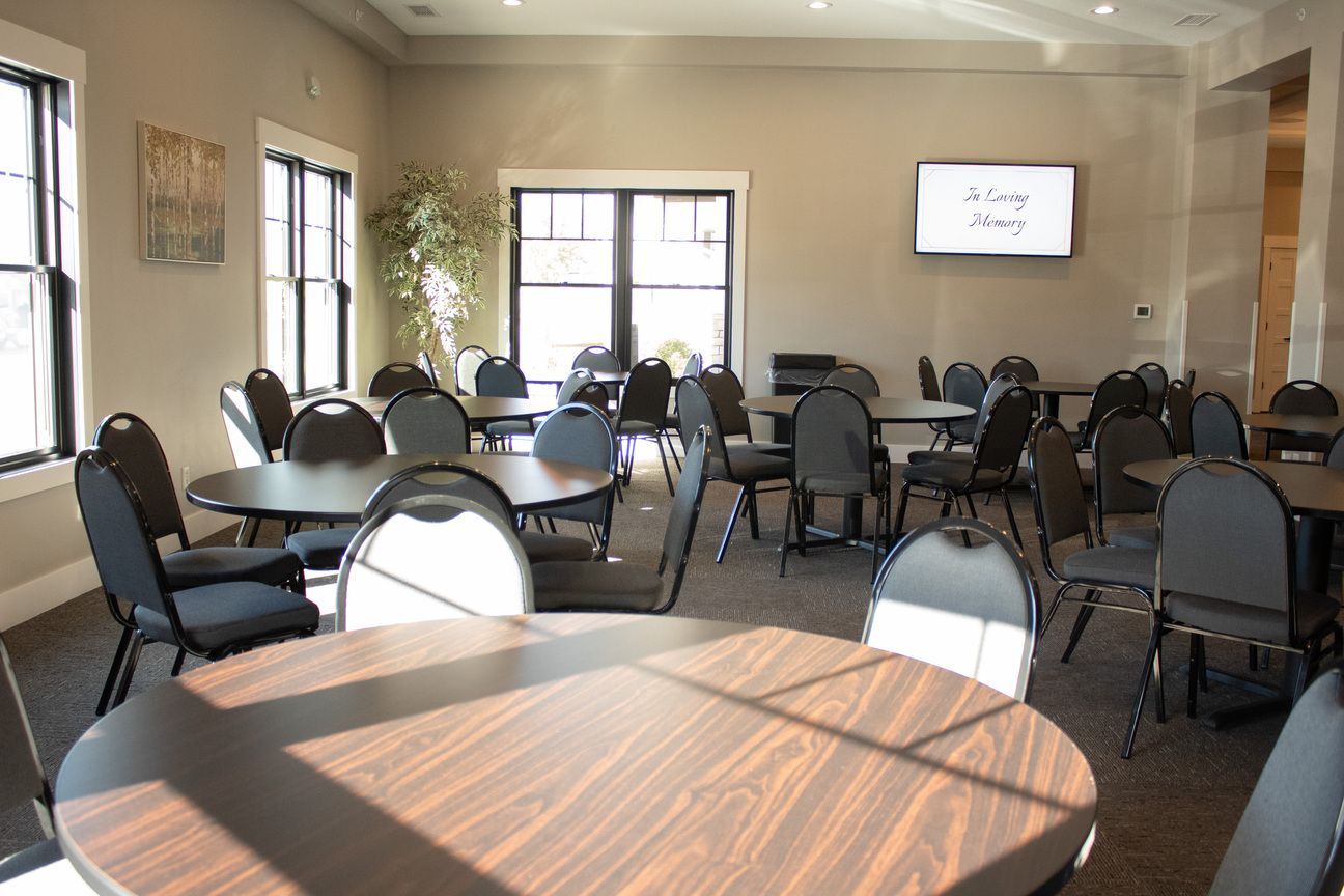 Empty meeting room with round tables, black chairs, and a presentation screen near large windows