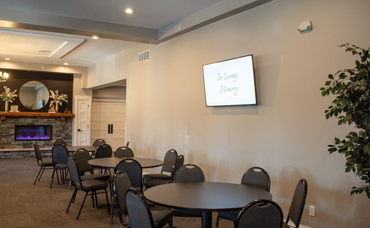 Quiet lounge with round tables, chairs, a wall-mounted TV, and a fireplace in the background.