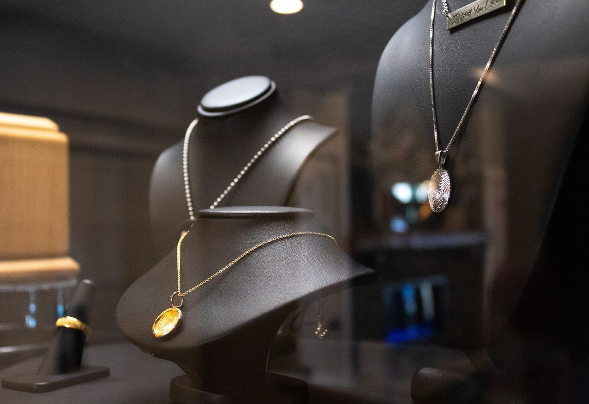Jewelry display with black bust stands showcasing gold and silver necklaces in a store window