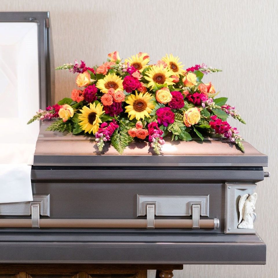 Colorful floral arrangement on a dark casket at a funeral home