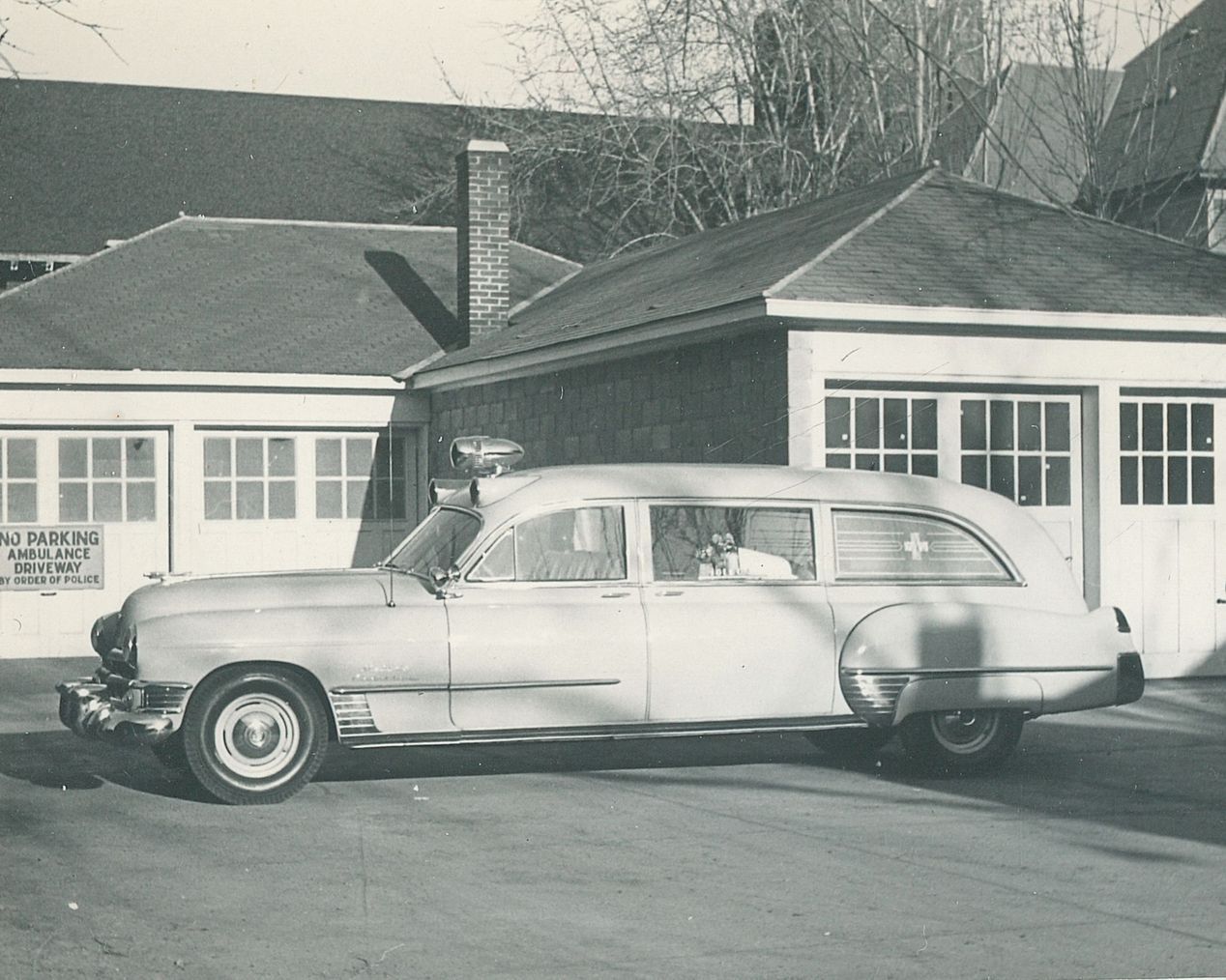 Vintage white station wagon parked in front of a garage and house, black-and-white photo