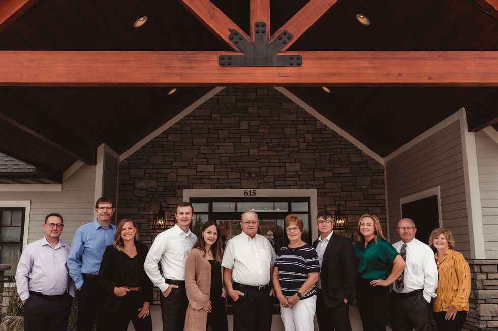 Group of people standing in front of a stone fireplace under a wooden pavilion