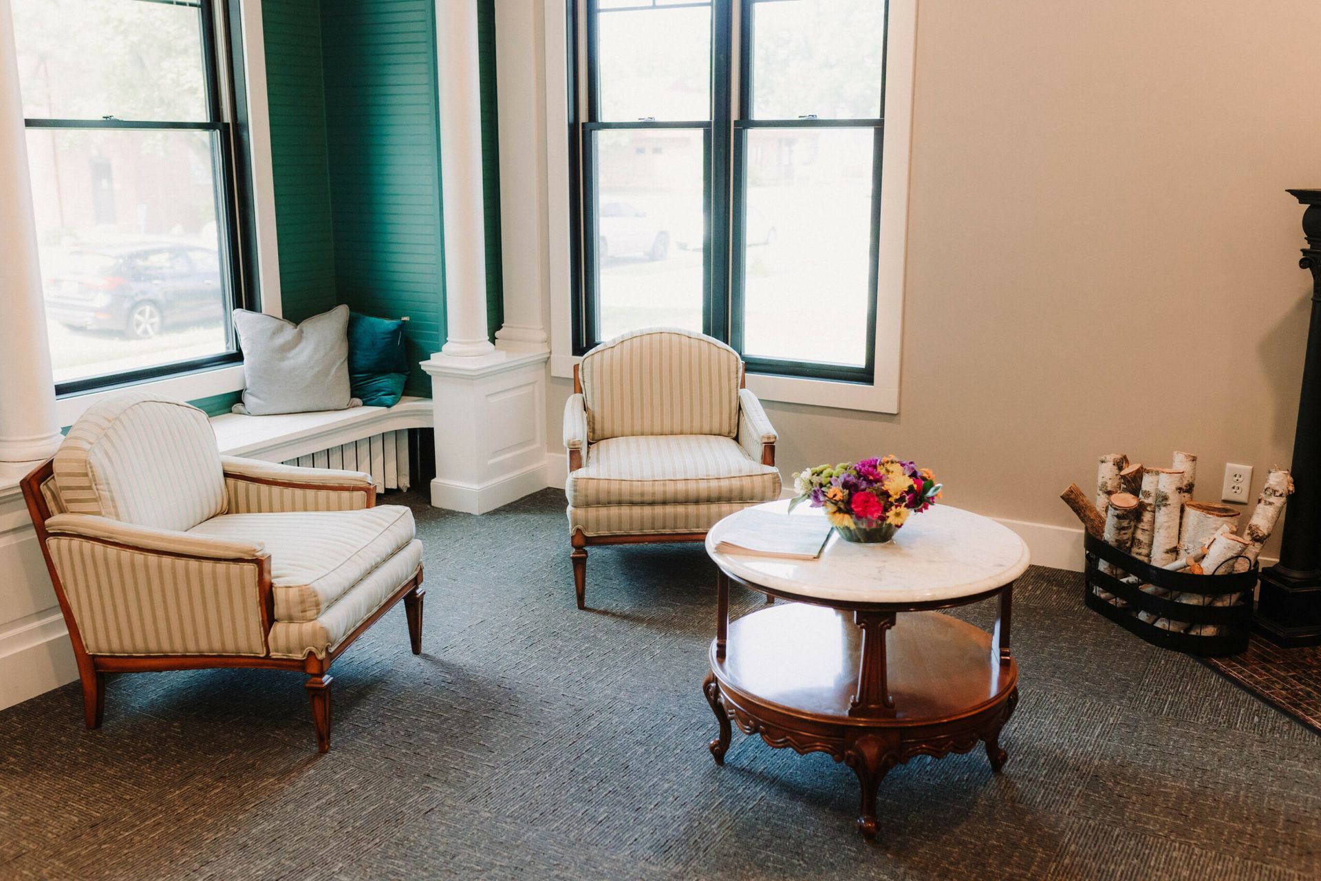 Bright sitting room with wicker chairs, round table, flowers, and large windows