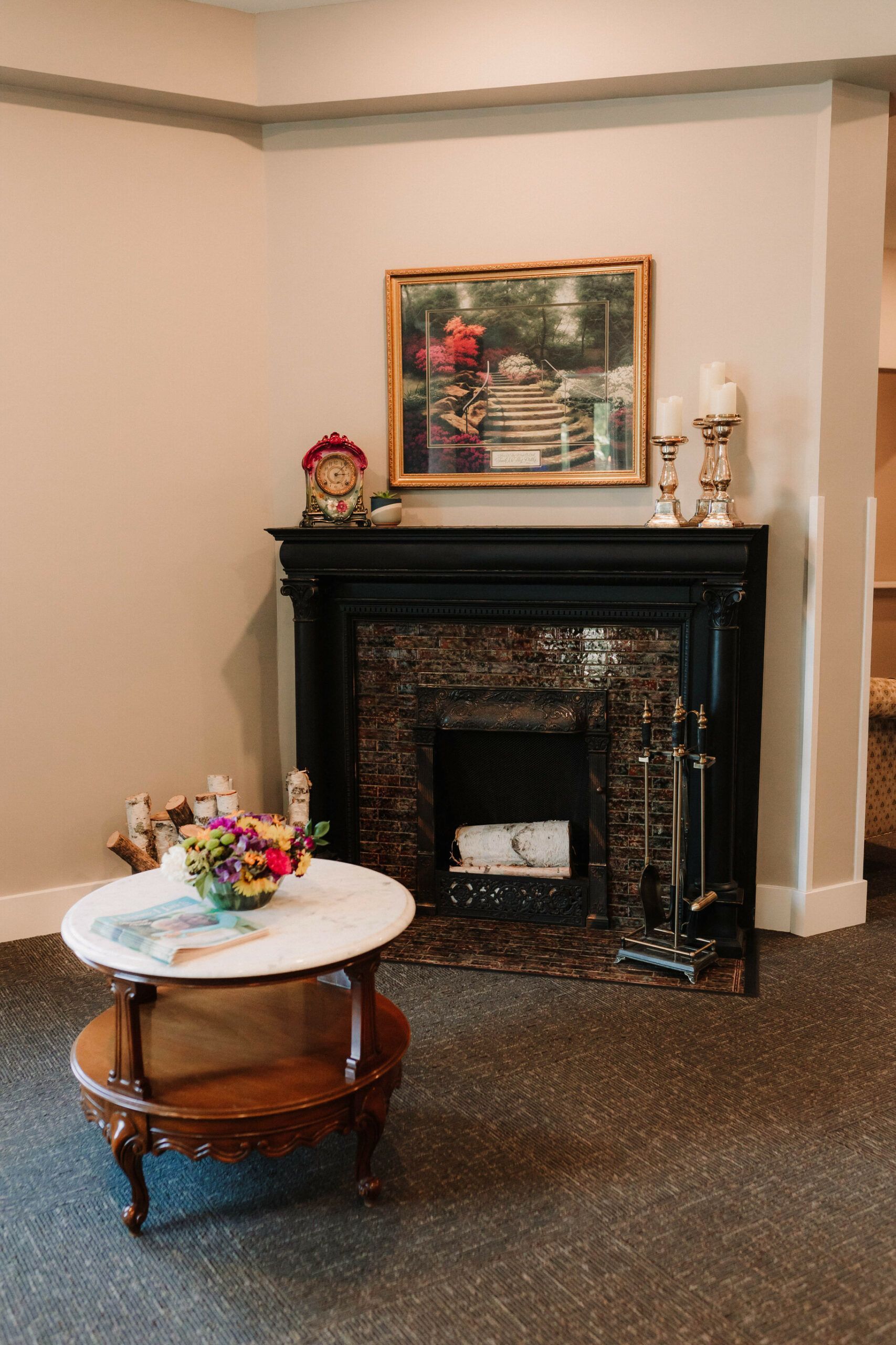 Cozy living room corner with black fireplace, framed art, and small round table with flowers