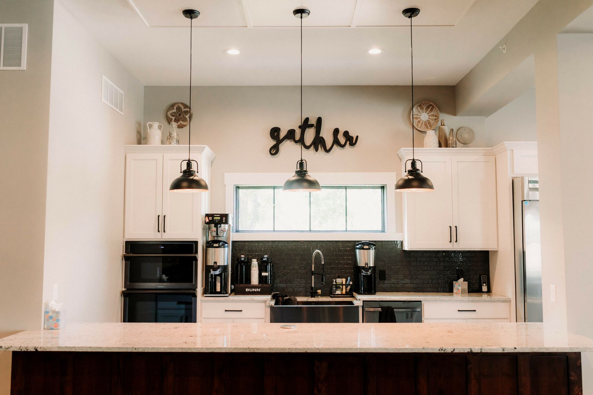 Modern kitchen with white cabinets, black pendant lights, and a dark wood island counter