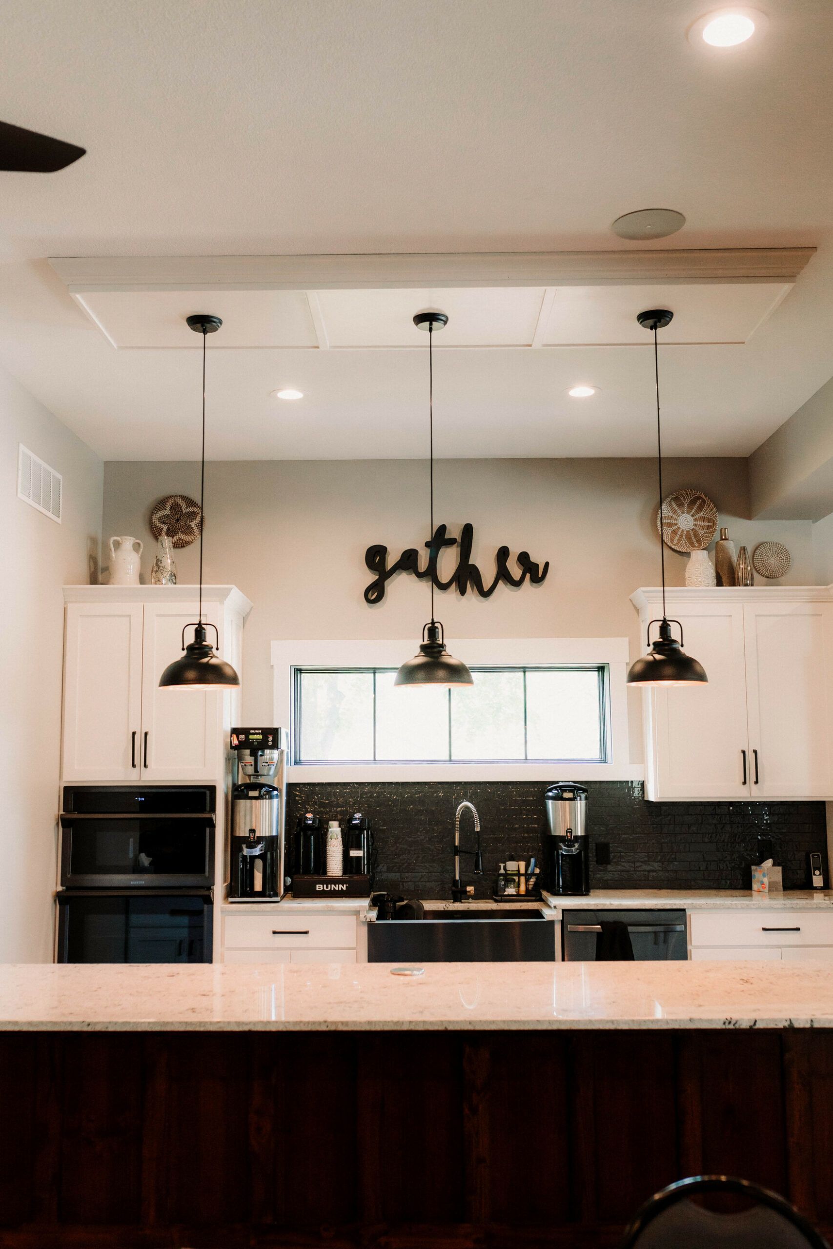 Modern kitchen with white cabinets, pendant lights, black backsplash, and dark wood island