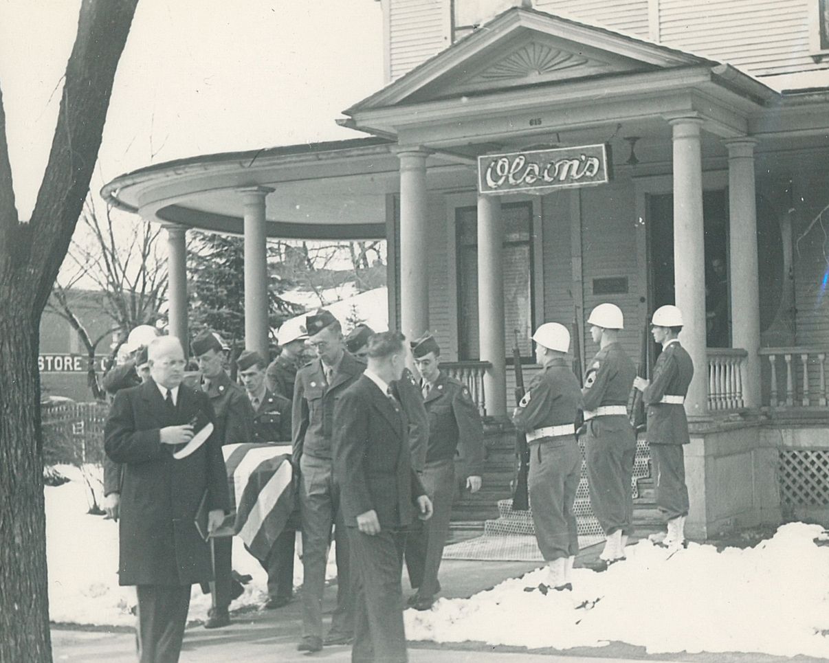 People gathered outside a winter storefront with snow on the ground and a Coca-Cola sign above the entrance.