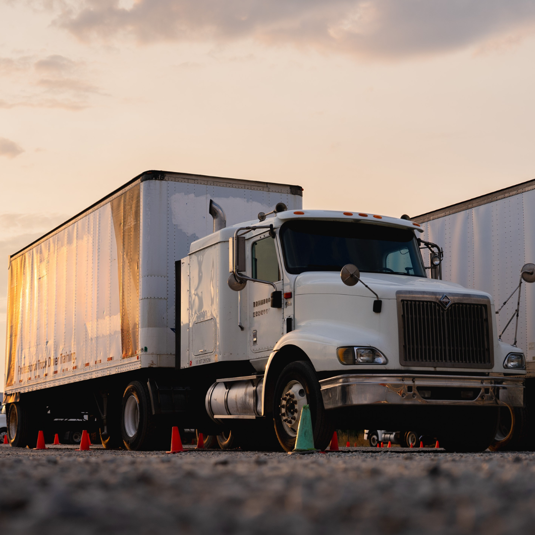 A white semi truck with a trailer is parked on the side of the road.