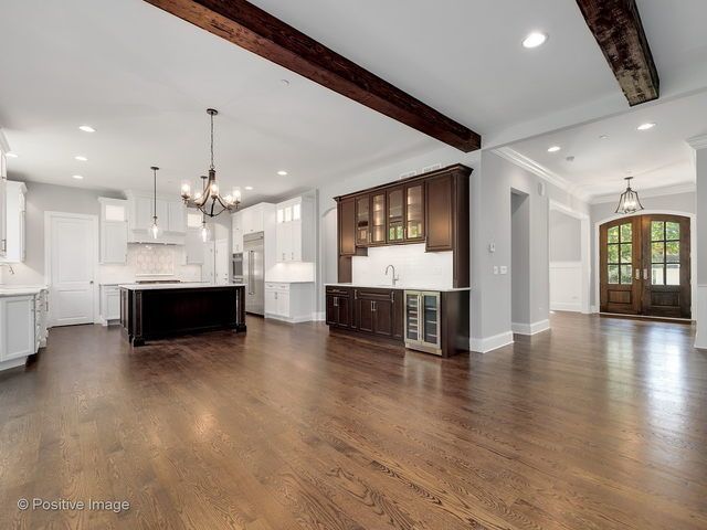An empty kitchen with hardwood floors and white cabinets