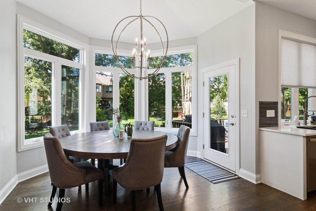 A dining room with a round table and chairs and a chandelier.