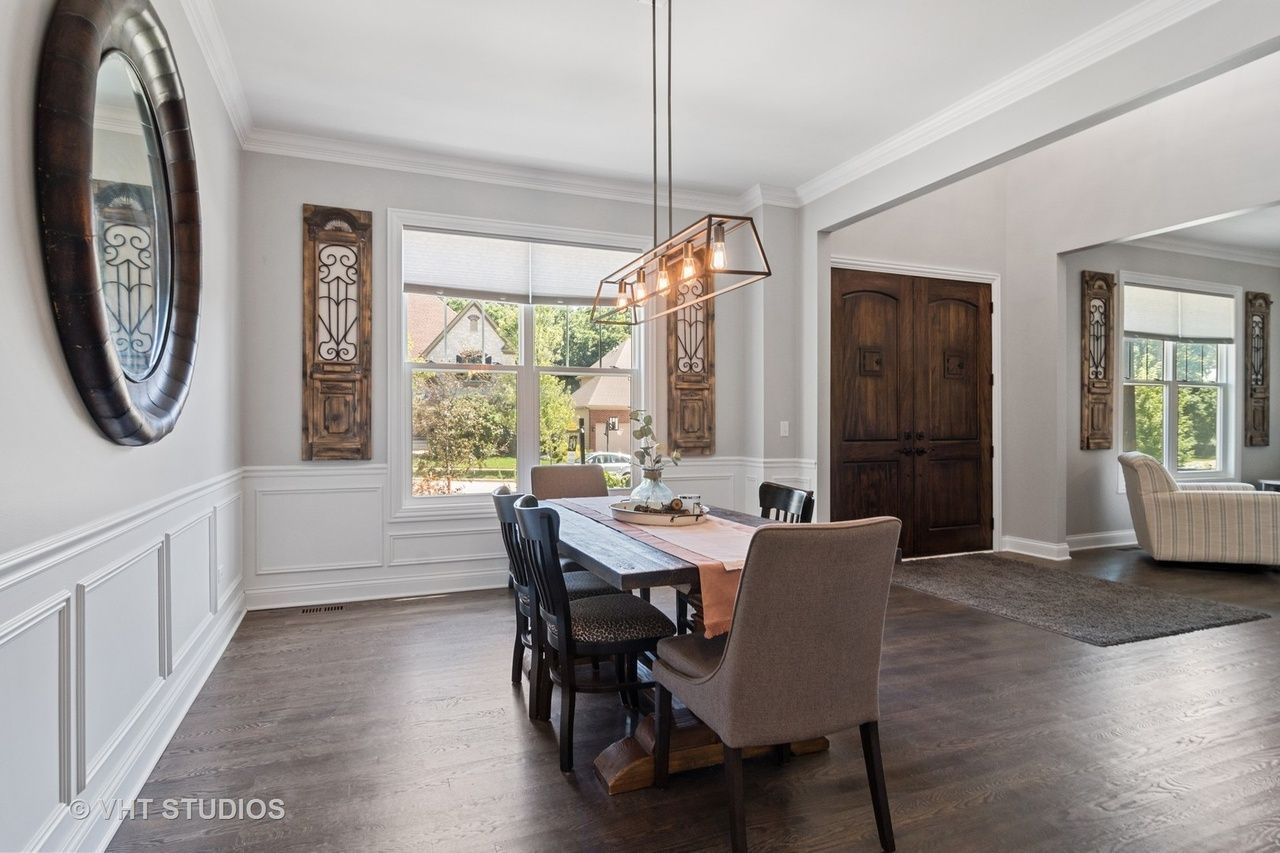 A dining room with a table and chairs and a mirror.