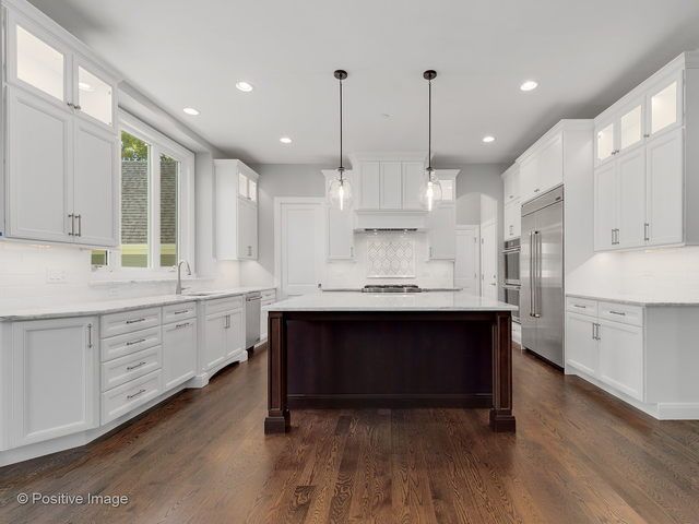 A kitchen with white cabinets and a large island in the middle.