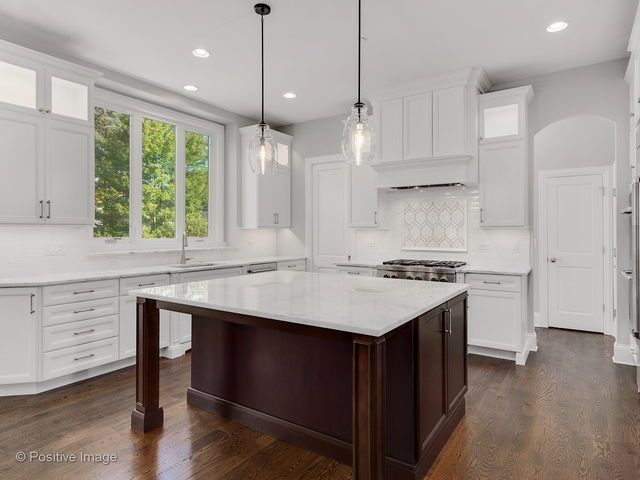 A kitchen with white cabinets and a large island in the middle