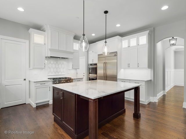 A kitchen with white cabinets and a large island in the middle.