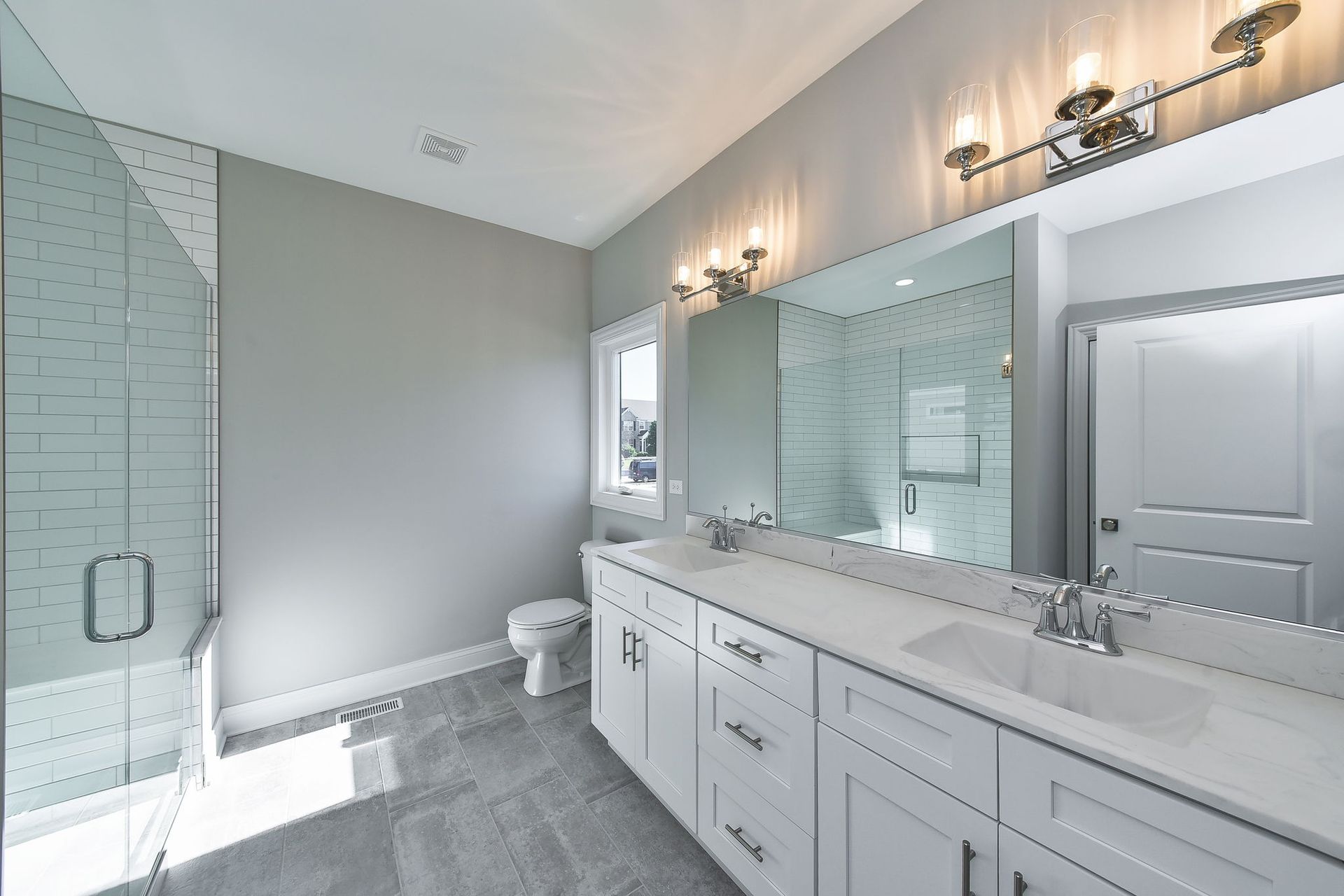 A bathroom with two sinks , a toilet , and a large mirror.