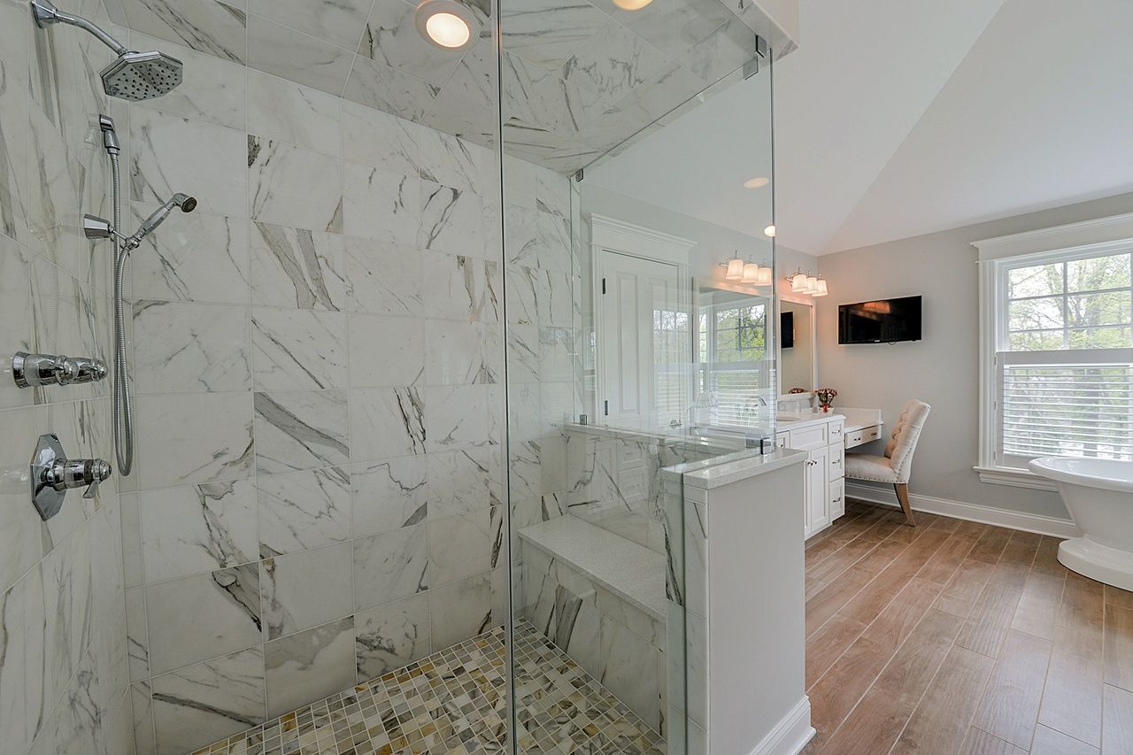 A bathroom with a walk in shower and marble walls.