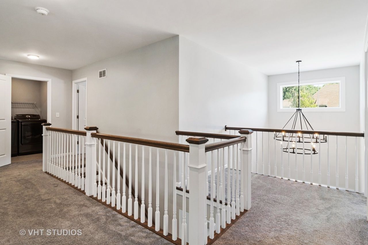 A staircase in a house with a white railing and a chandelier.