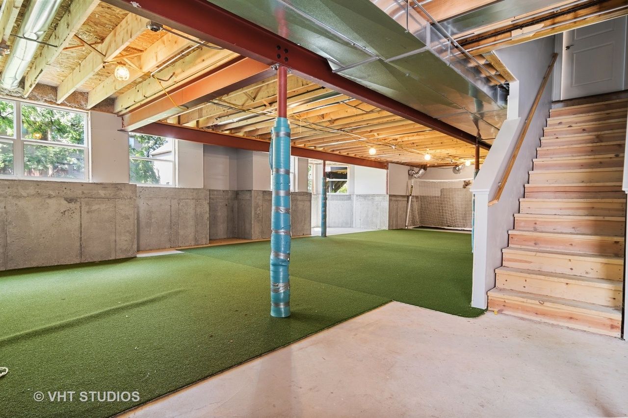 A large empty basement with stairs and a green carpet.