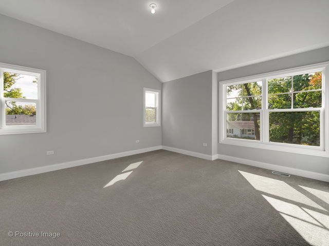 An empty room with a vaulted ceiling and two windows.