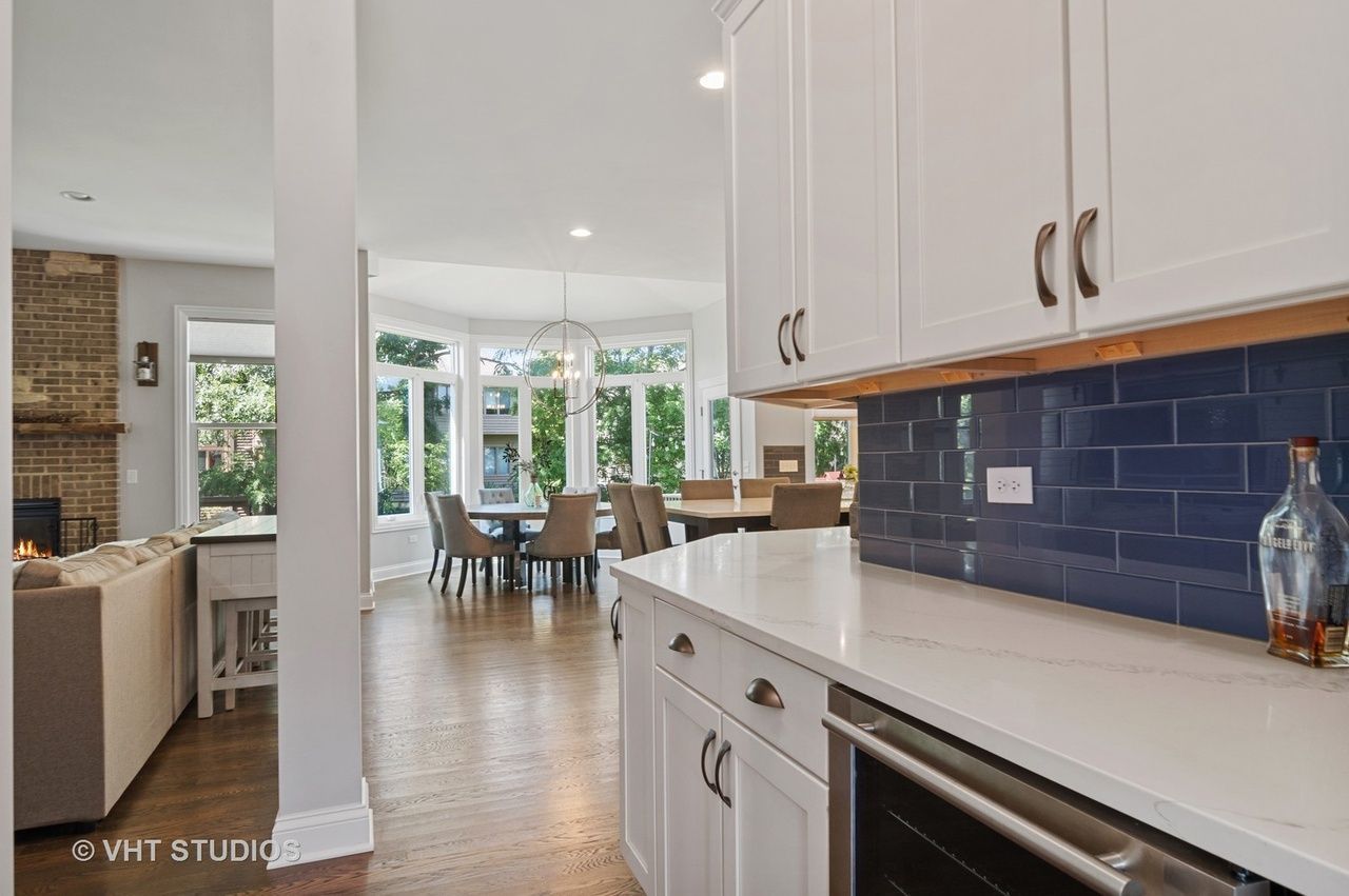 A kitchen with white cabinets and blue tiles and a bottle of whiskey on the counter.