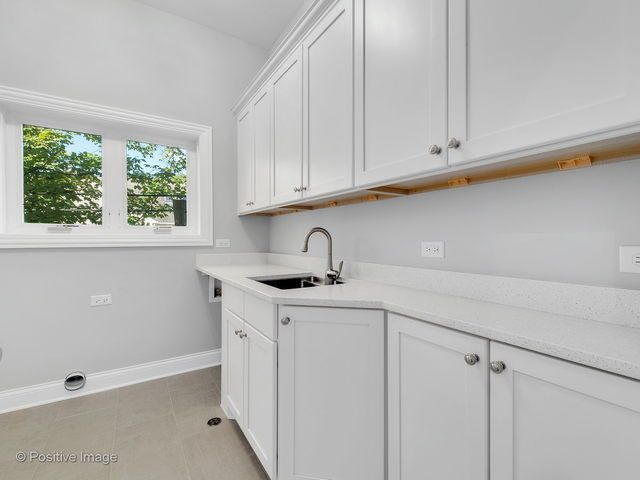 A laundry room with white cabinets and a sink