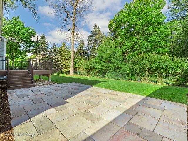 A patio with a deck and trees in the background