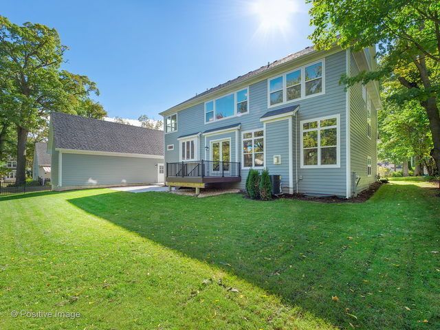The back of a house with a large lawn and a deck.