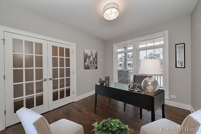 A home office with a desk , chairs and a lamp