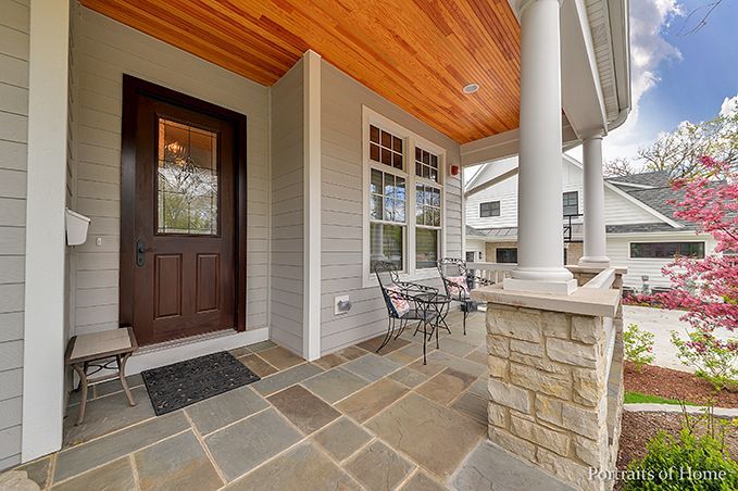 There is a porch with a table and chairs on it.