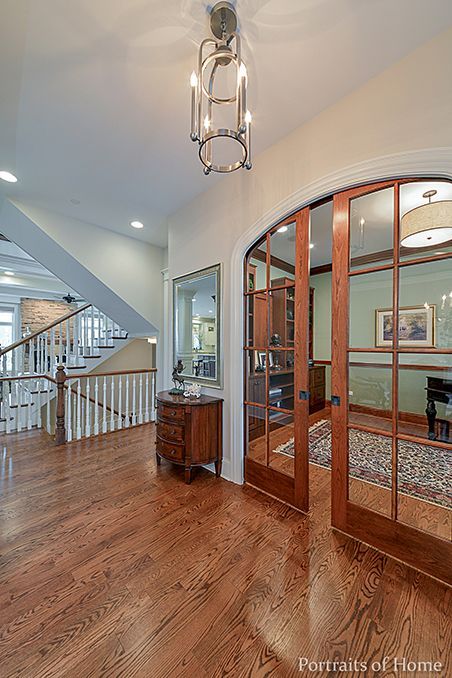 A hallway with hardwood floors and sliding glass doors leading to a staircase.