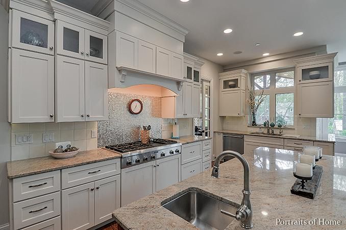 A kitchen with white cabinets , granite counter tops , stainless steel appliances and a sink.
