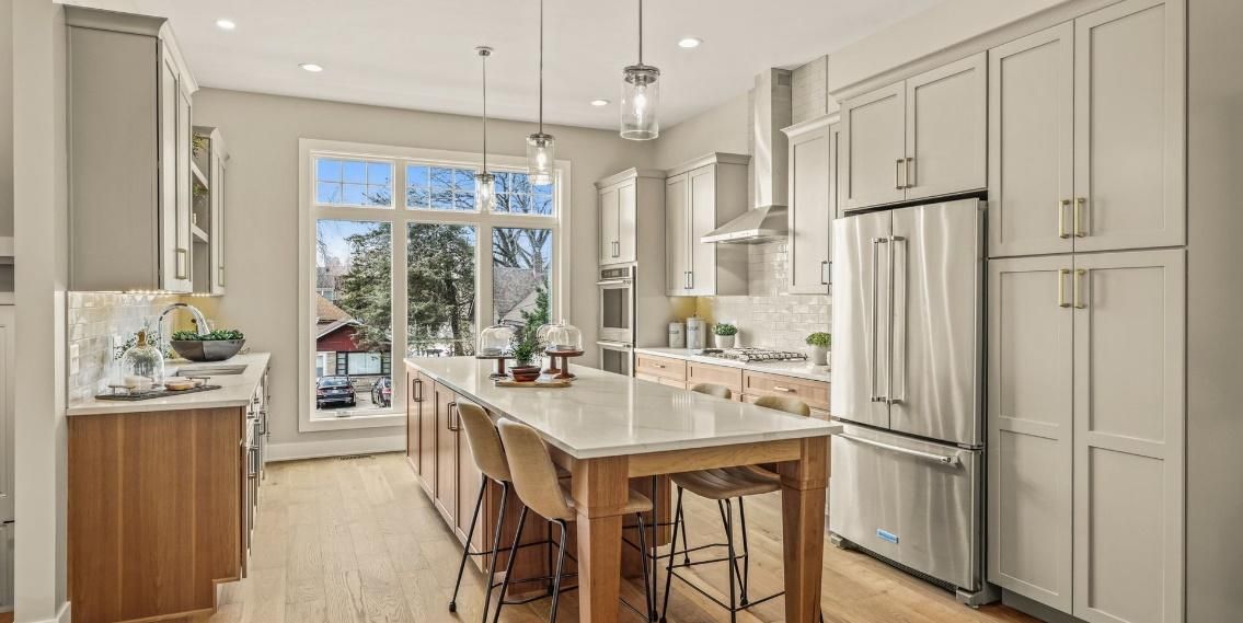 A kitchen with white cabinets and stainless steel appliances and a large island.