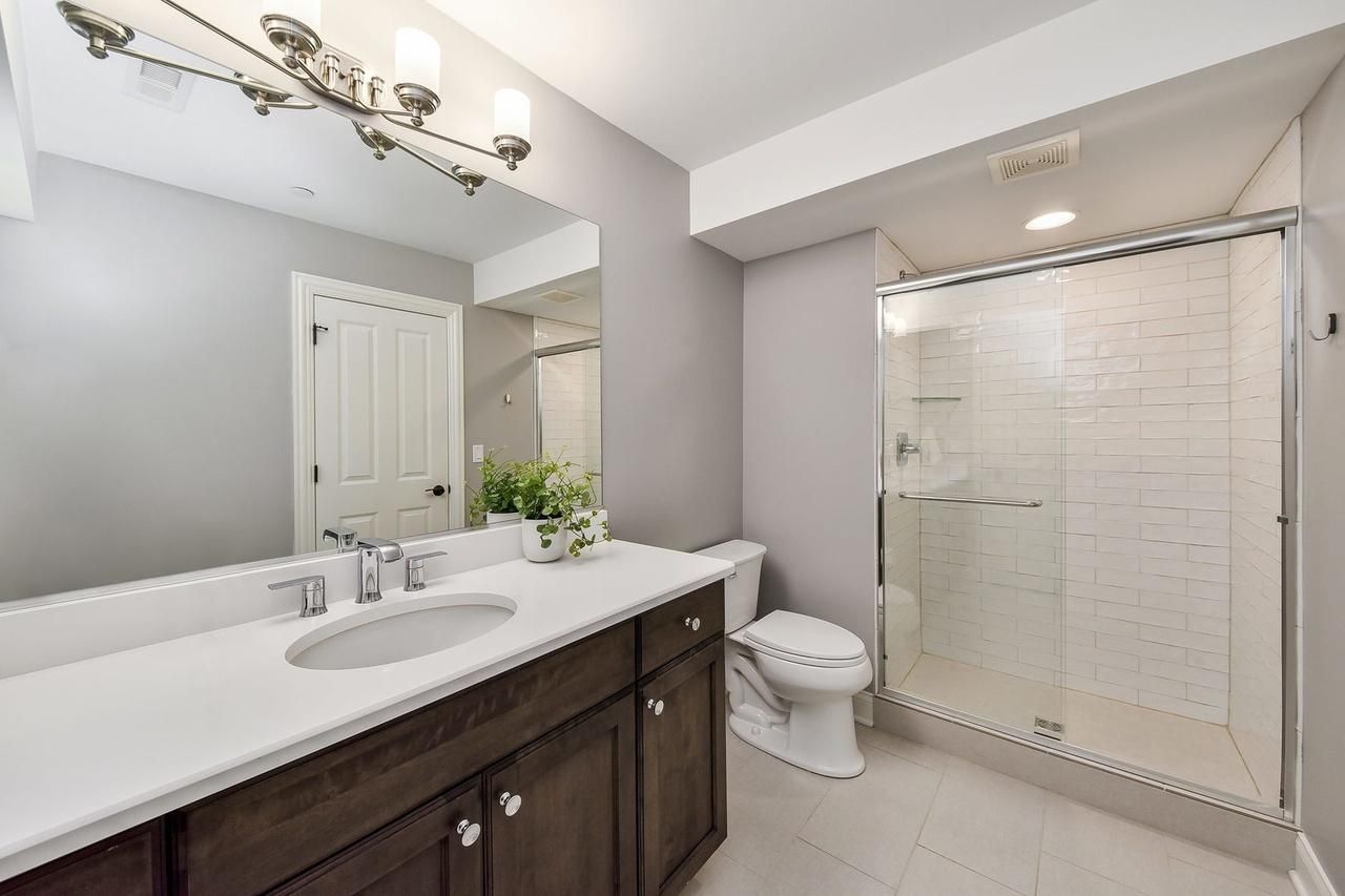 A bathroom with a sink , toilet , shower and mirror.