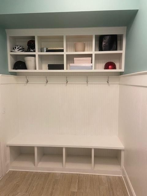 There is a bench in the middle of the room with shelves above it.