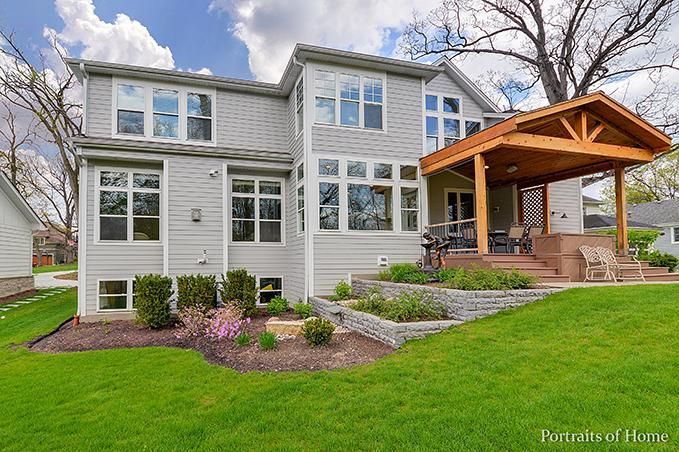 The back of a house with a wooden porch and a large lawn.