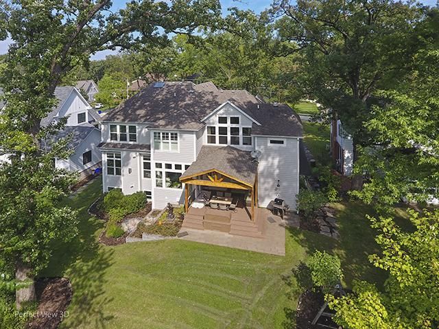An aerial view of a large house with a gazebo in the backyard surrounded by trees.