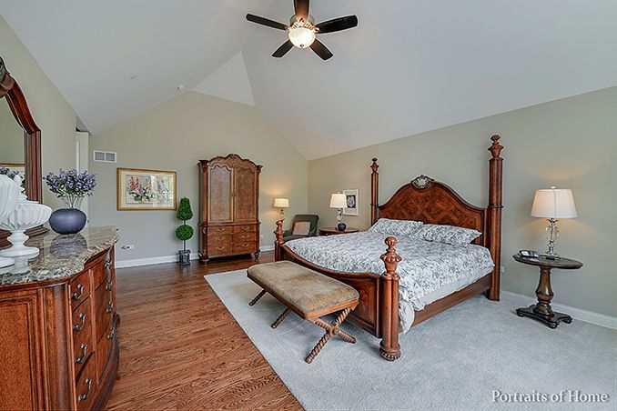 A bedroom with a bed , dresser , mirror and ceiling fan.