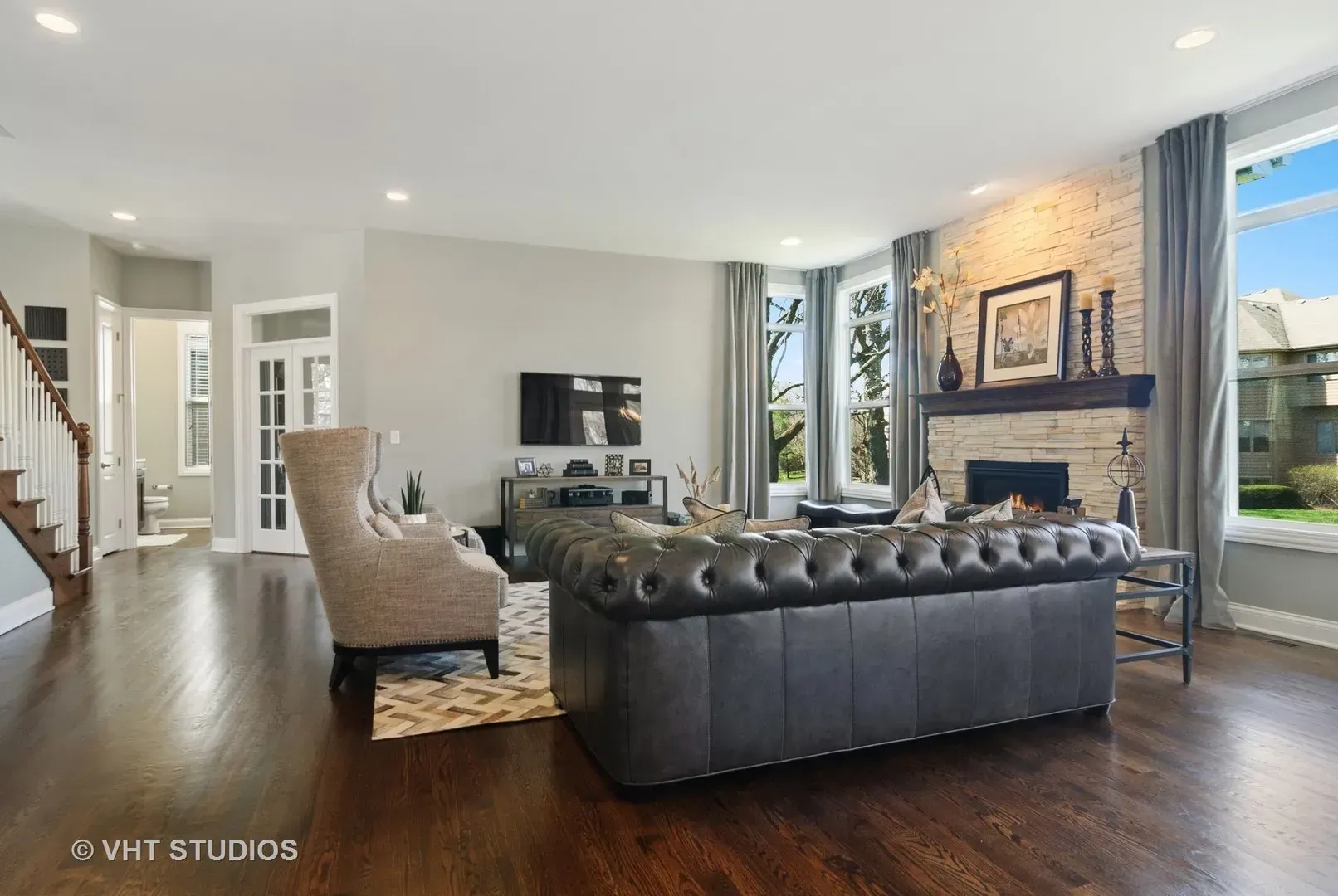 A living room with a couch , chairs , television and fireplace.