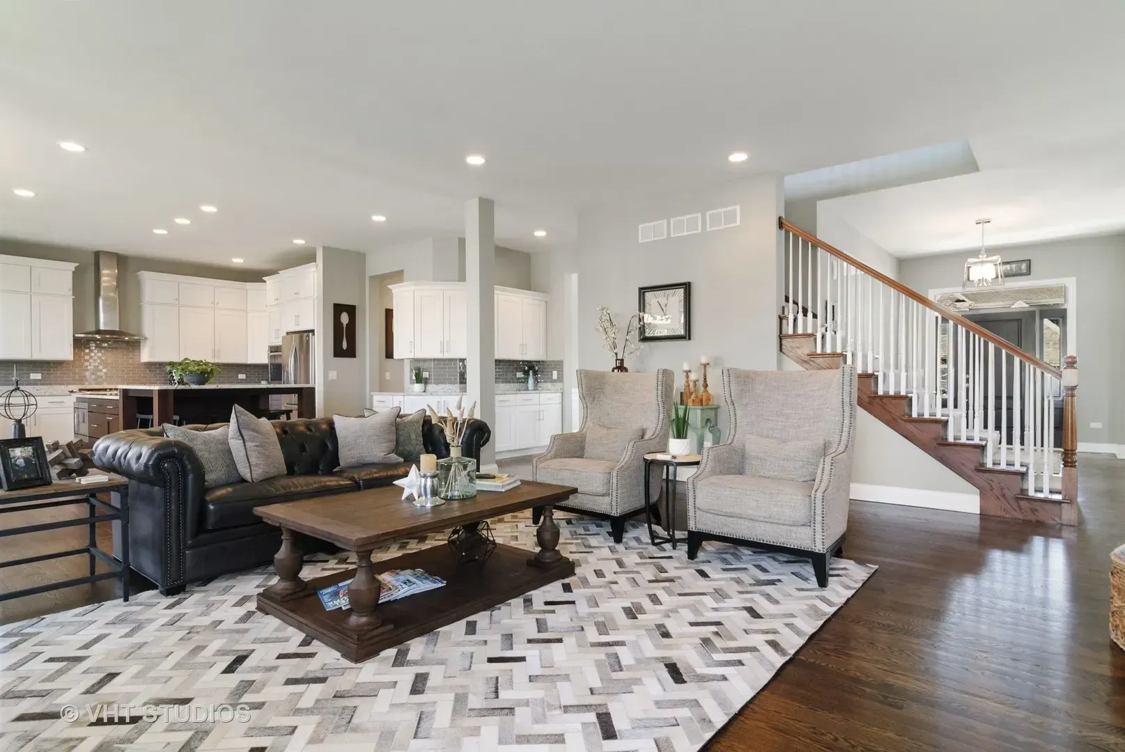 A living room with a couch , chairs , coffee table and rug.