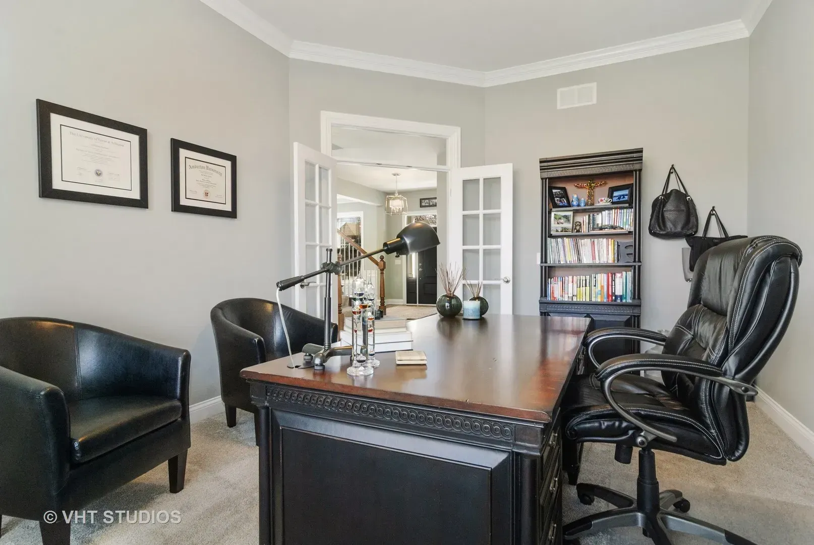A home office with a desk , chairs and a bookshelf.