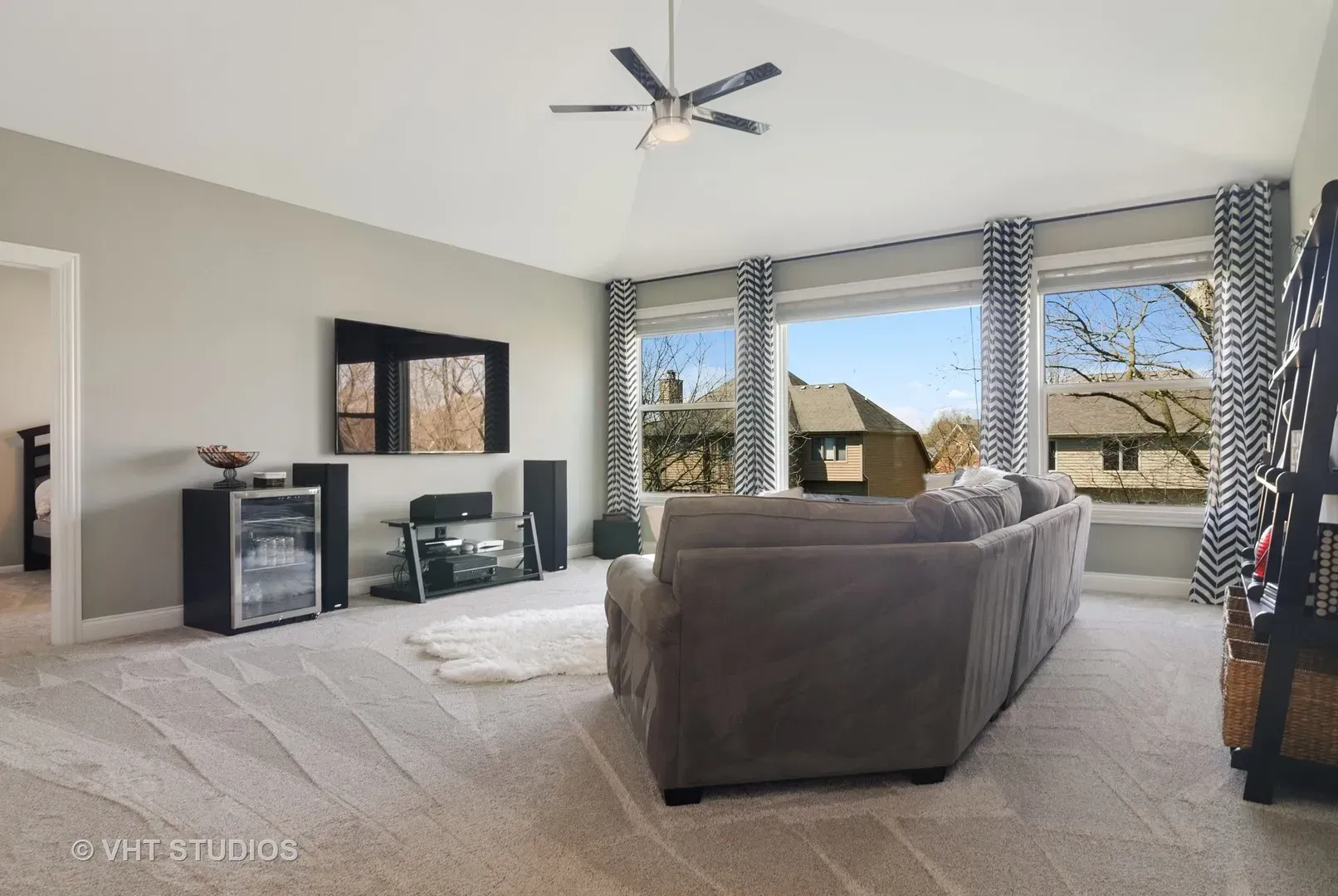 A living room with a couch a television and a ceiling fan