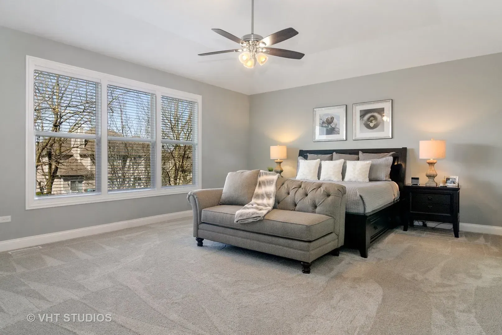 A bedroom with a bed , couch , nightstands , and a ceiling fan.