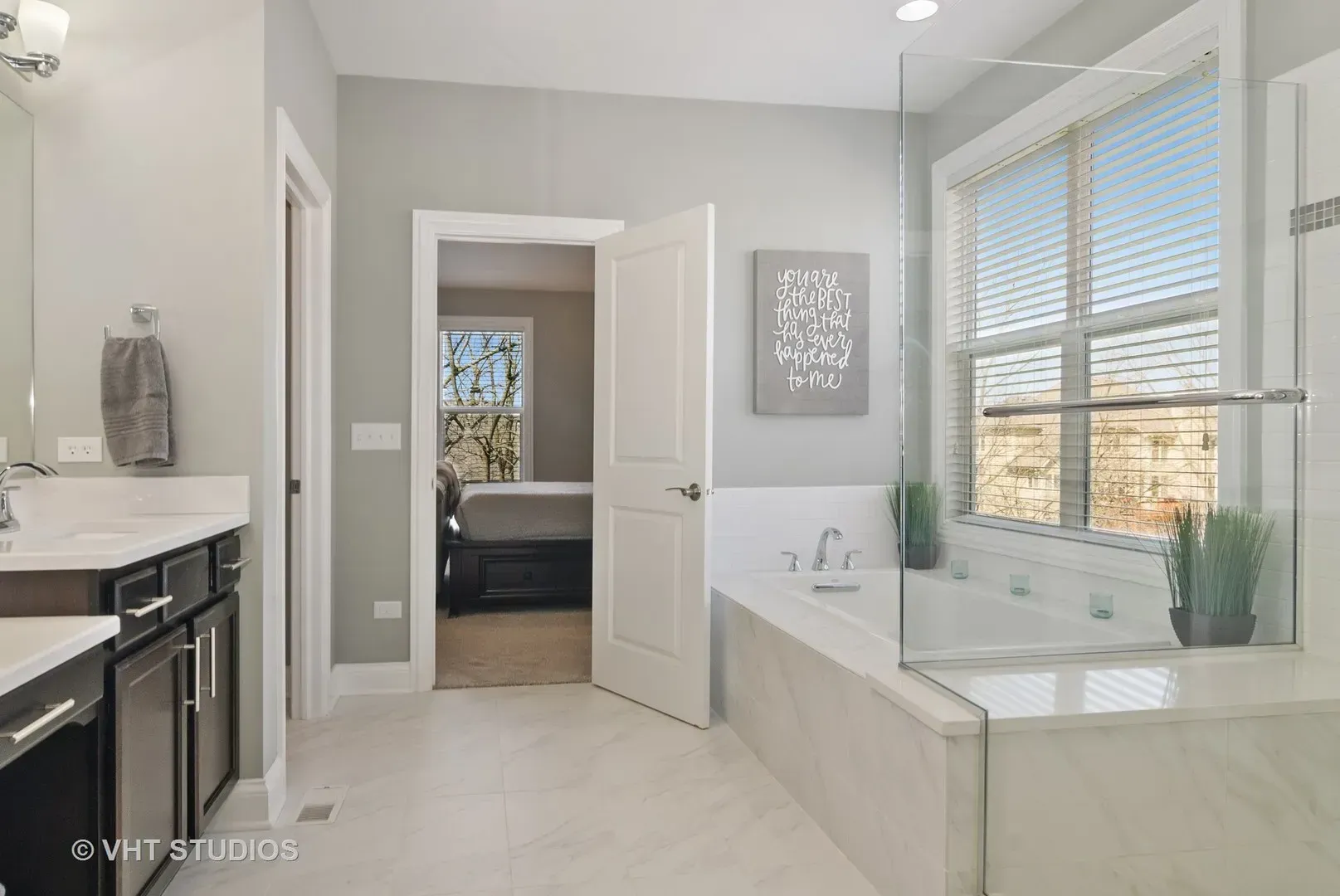 A bathroom with a tub , sink , mirror and window.