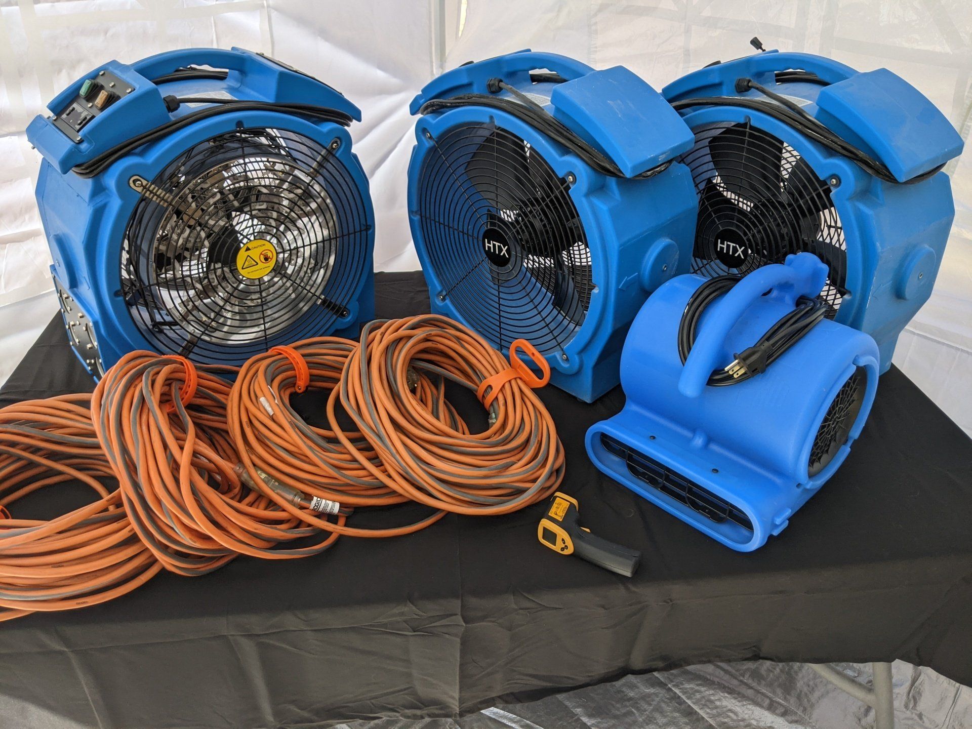 Two blue fans are sitting on a table next to a bunch of wires